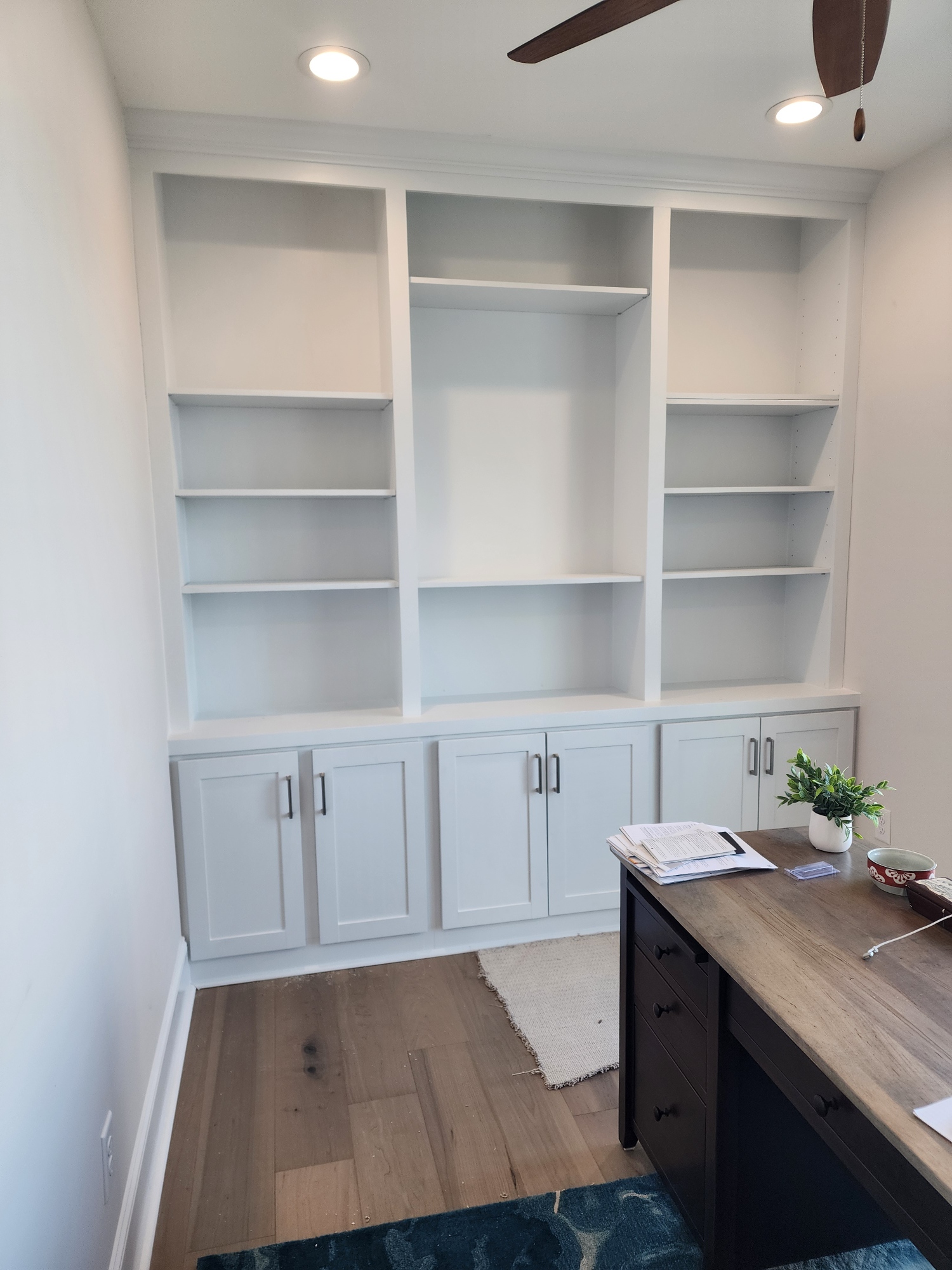 Office space with custom white built-in shelves and cabinets
